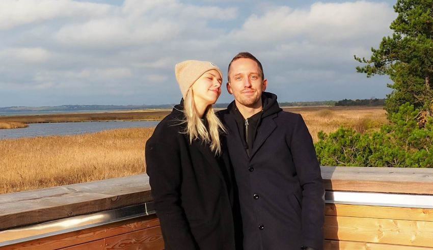 A man and woman posing for a photo on a wooden deck.