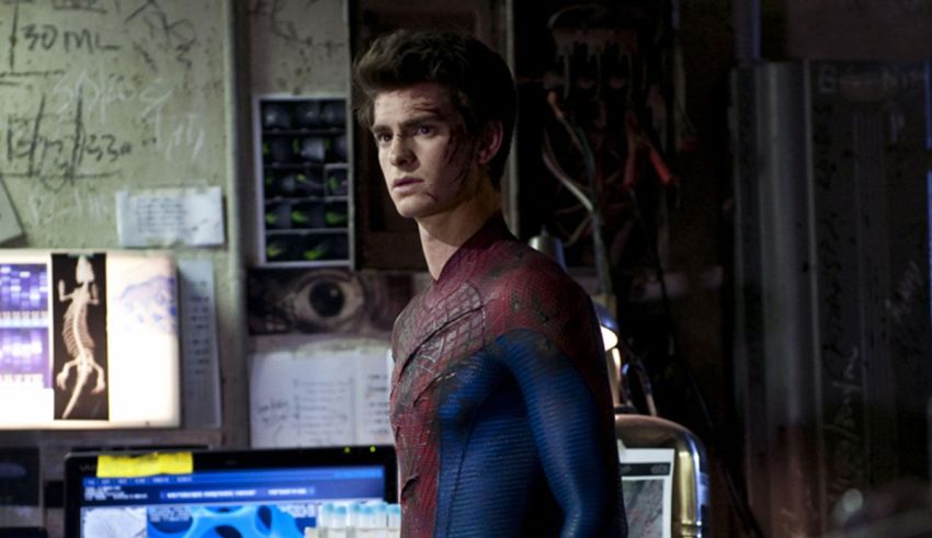 The amazing spider - man is standing in front of a computer.