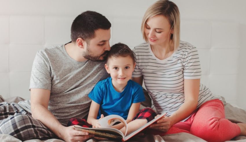 A man and woman reading a book to their son in bed.