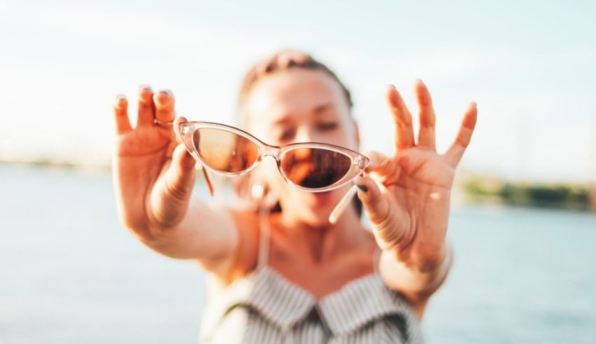 A woman is holding her sunglasses up to the camera.