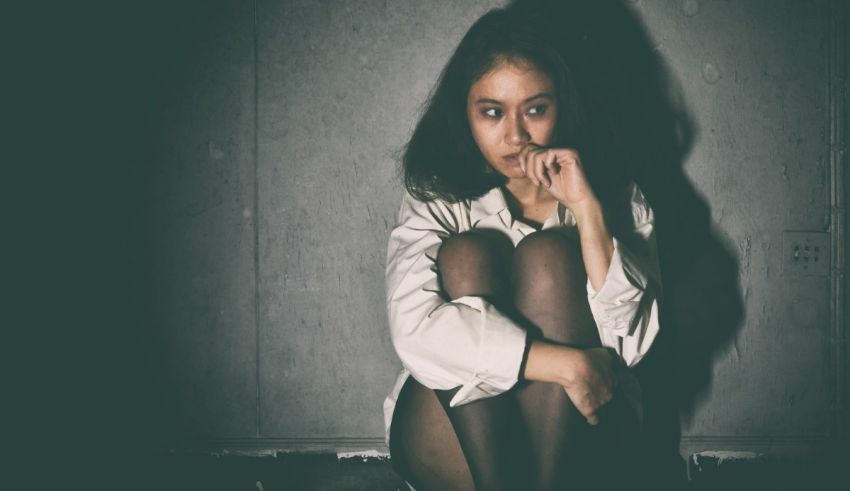 A girl sitting on the floor in a dark room.