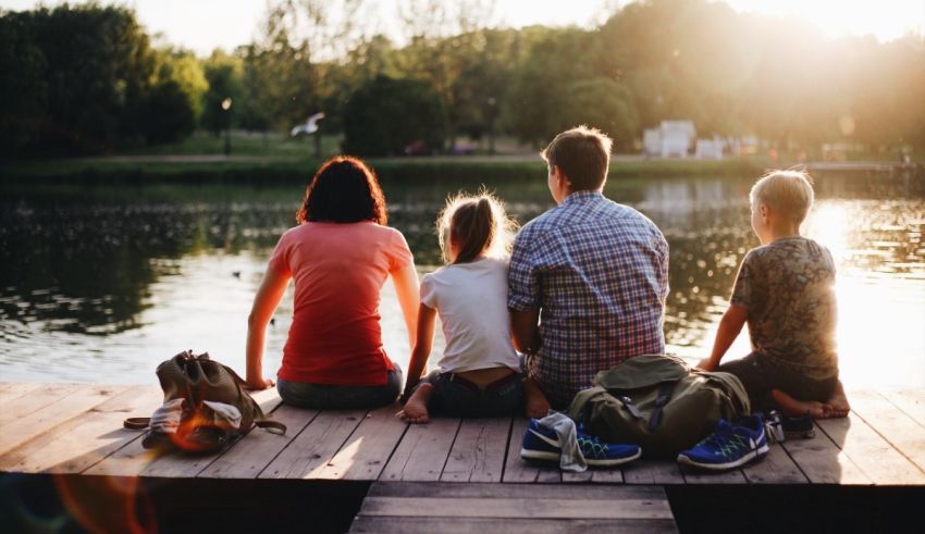 A family sits on a dock overlooking a lake.