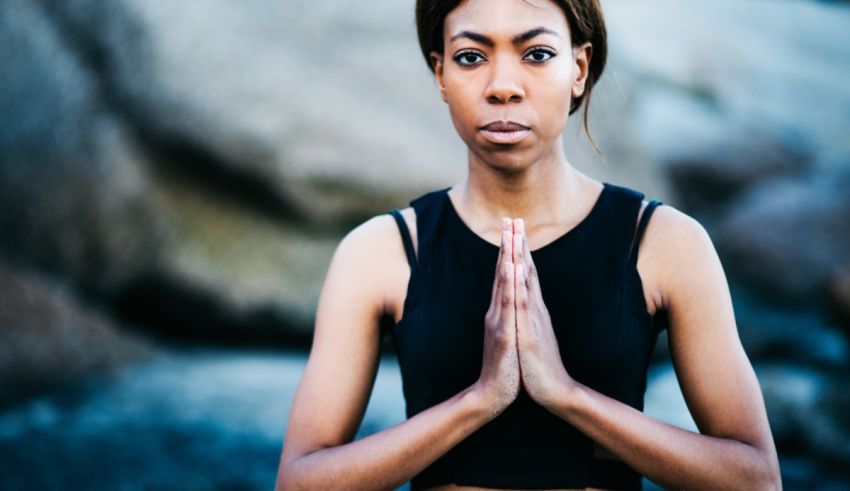 A black woman meditating with her hands folded.