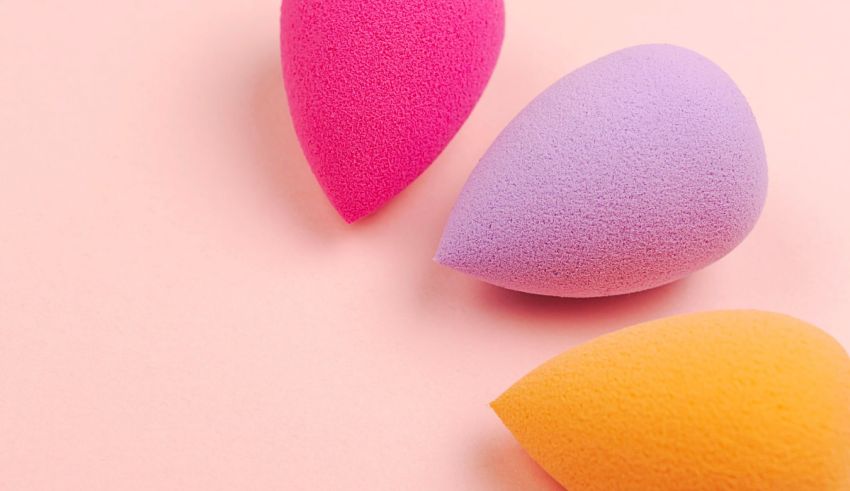 Three makeup sponges on a pink background.