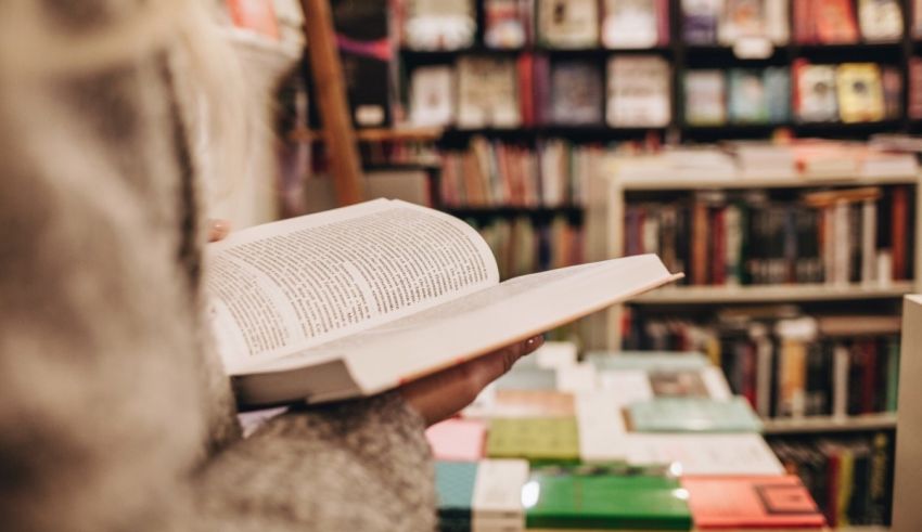 A woman is reading a book in a book store.