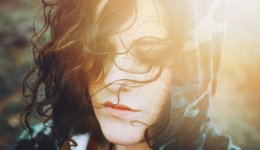 A woman in a camouflage hoodie looking at the sun.