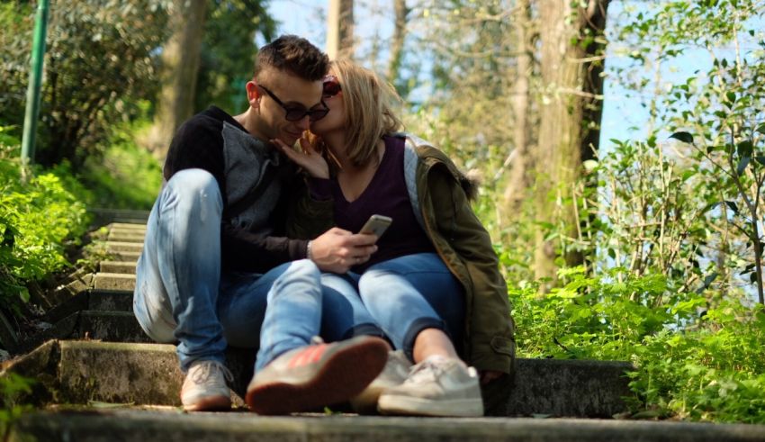 A man and woman sitting on steps in the woods.