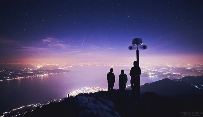 Three people standing on top of a mountain at night.