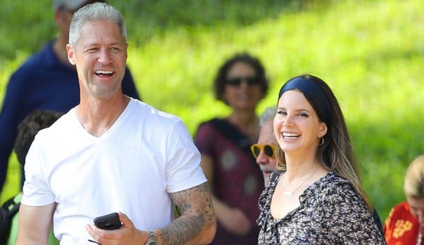 A man and woman smiling while walking in a park.