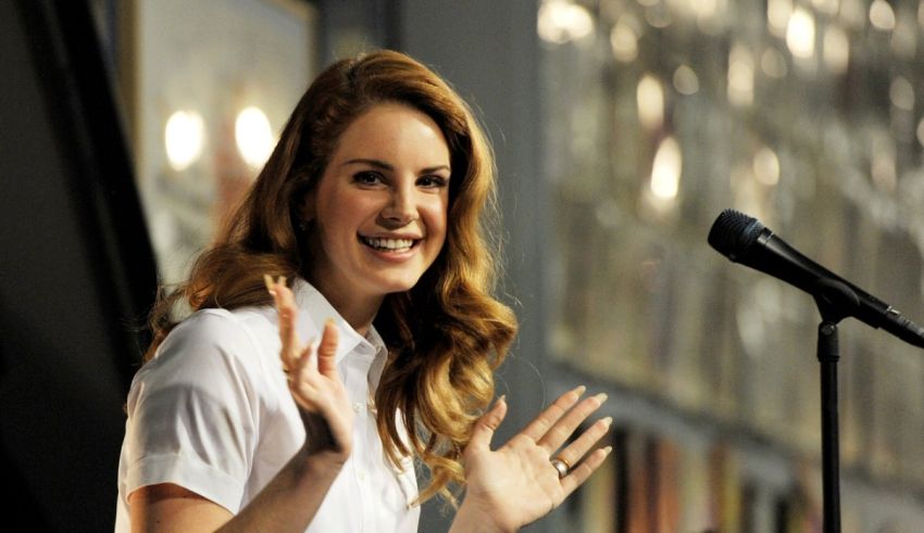 A woman in a white shirt is speaking into a microphone.