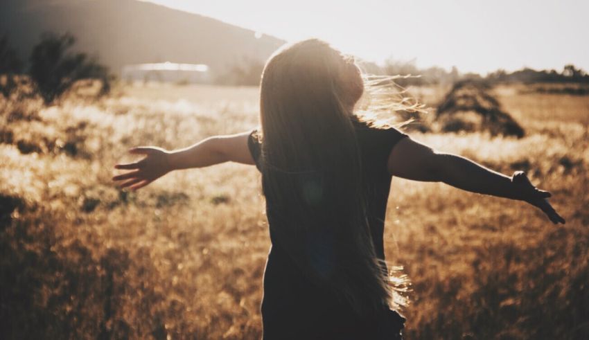 A girl in a field with her arms outstretched.