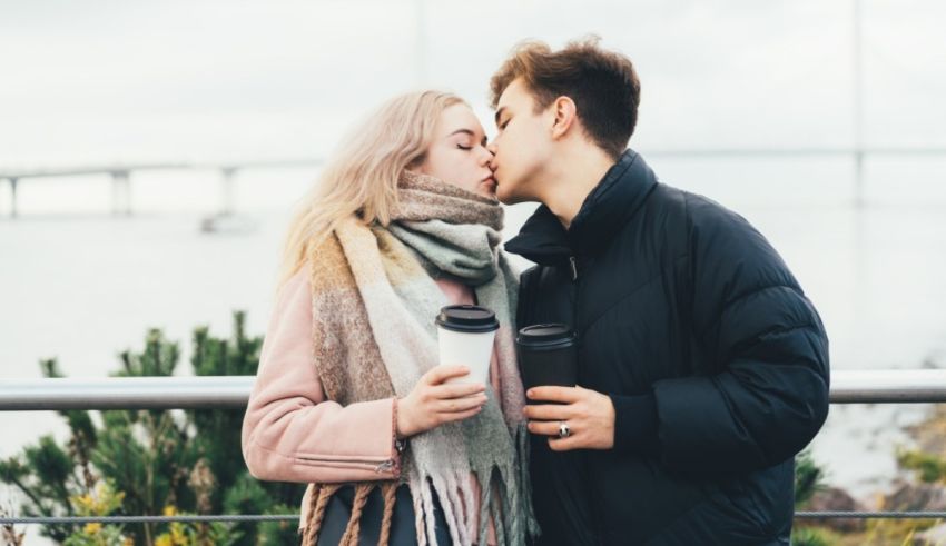 A couple kissing in front of a bridge.