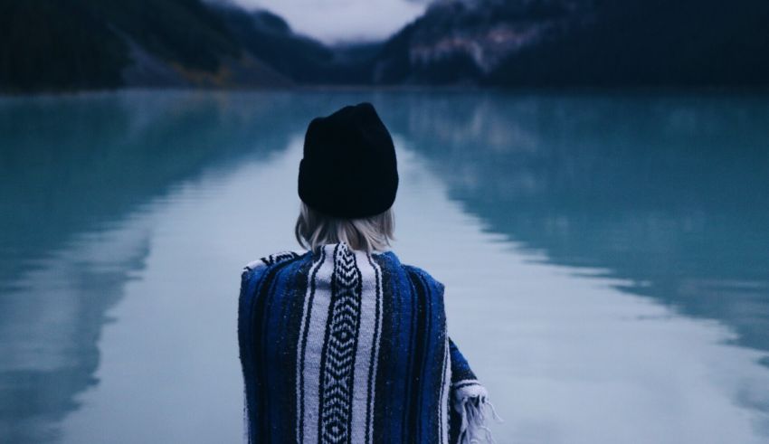 A woman looking out over a lake with mountains in the background.