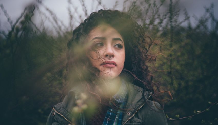 A woman with curly hair standing in a field.