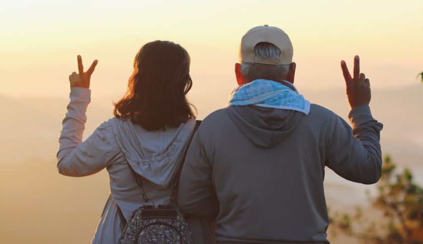 A couple making a peace sign while standing on top of a mountain.