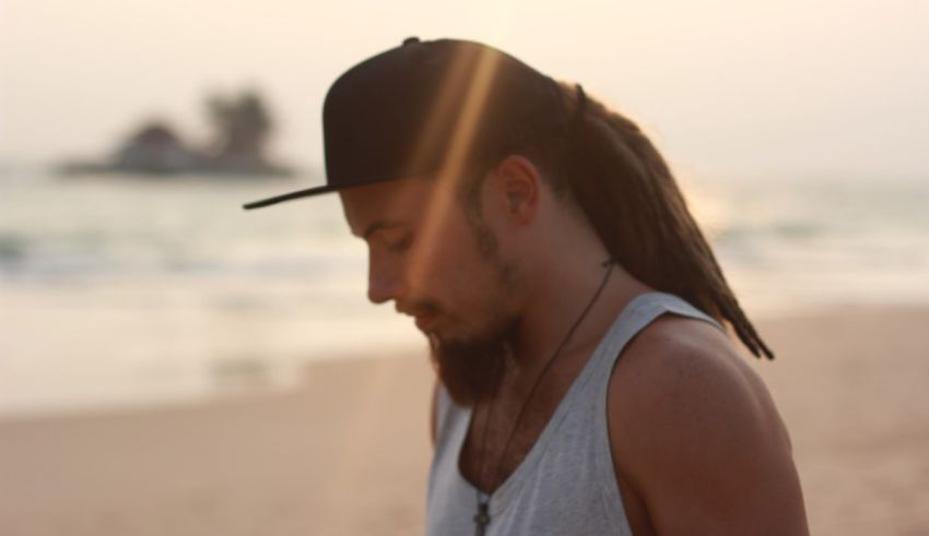 A man with dreadlocks standing on the beach.