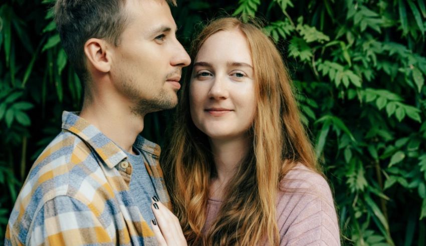 A man and woman are posing in front of a green wall.