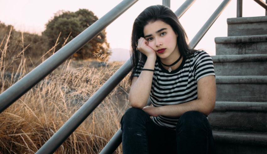 A girl sitting on stairs with her hand on her face.