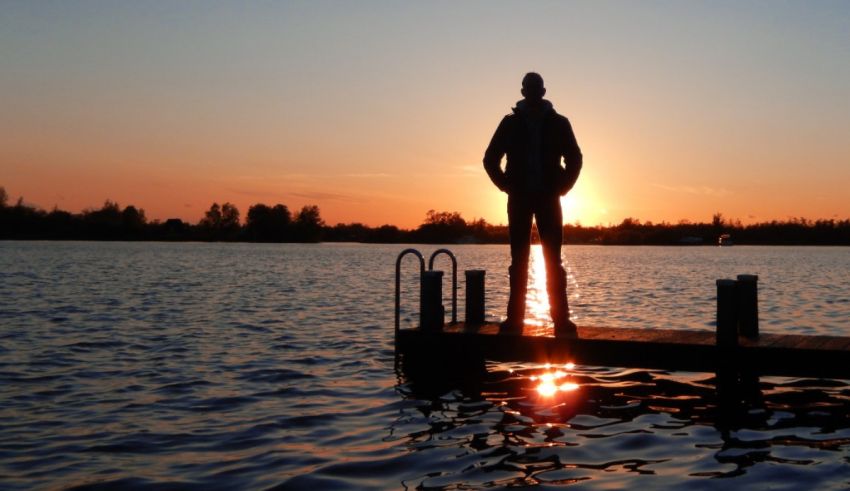 A man standing on a dock at sunset.