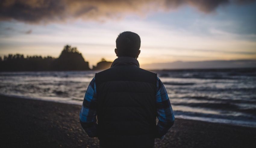 A man standing on a beach at sunset.