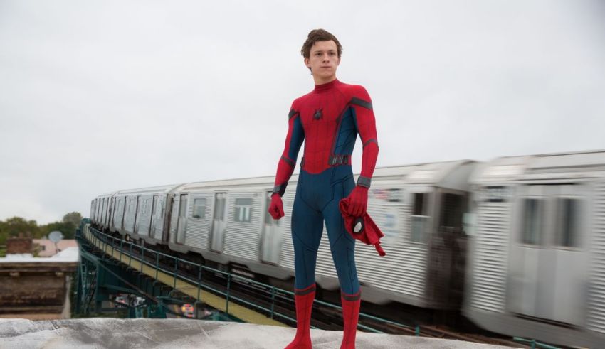 Spider - man stands on top of a train track.