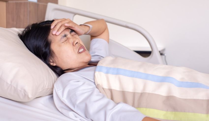 A woman is lying in a hospital bed with a headache.