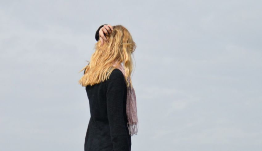 A woman standing on a beach with her back to the sky.