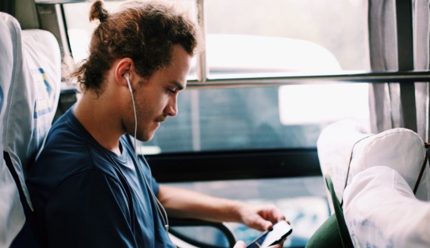 A man sitting on a bus looking at his phone.