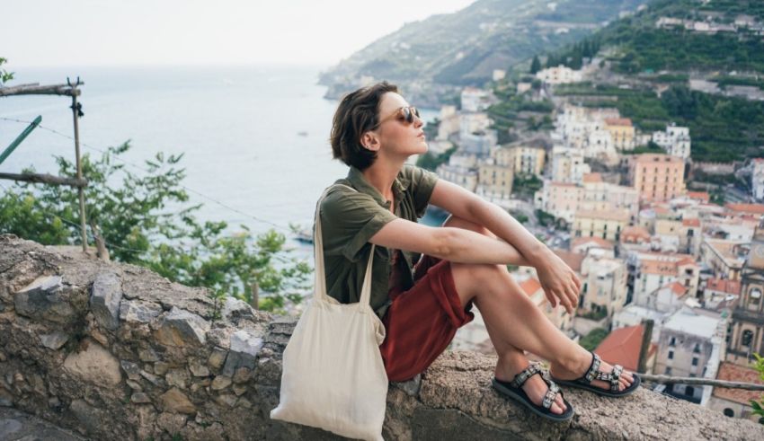 A woman is sitting on a ledge overlooking a city.