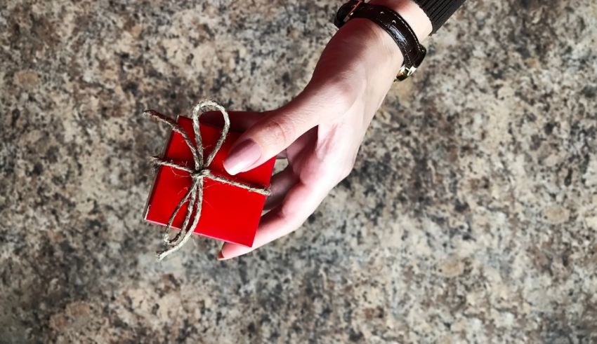 A woman's hand holding a red gift box.