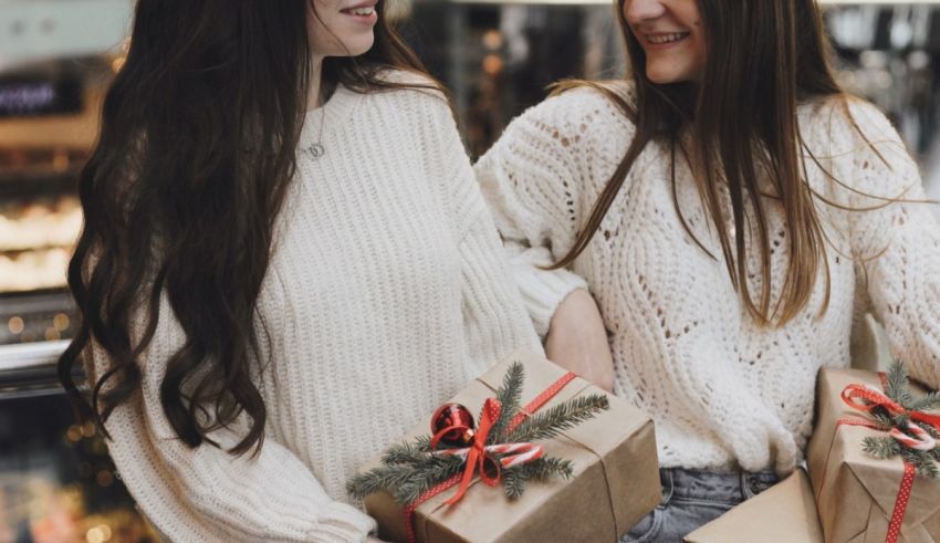 Two women holding gift boxes in a shopping mall.