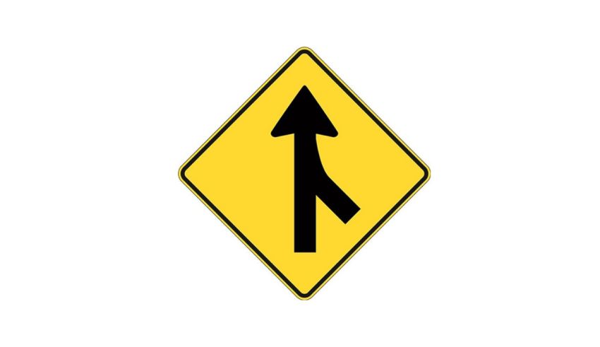 A yellow and black road sign with an arrow pointing in the opposite direction.