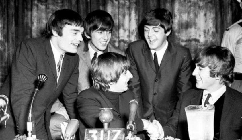 The beatles are posing for a picture at a table.