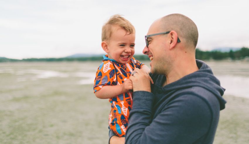 A man holding a baby on a beach.