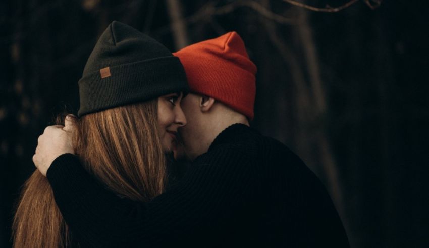 A man and woman hugging in the woods.