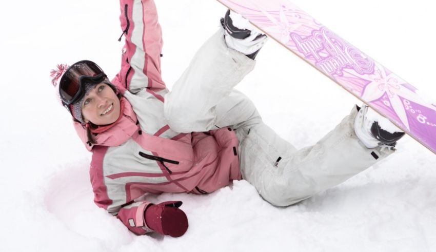 A girl with a snowboard laying down in the snow.