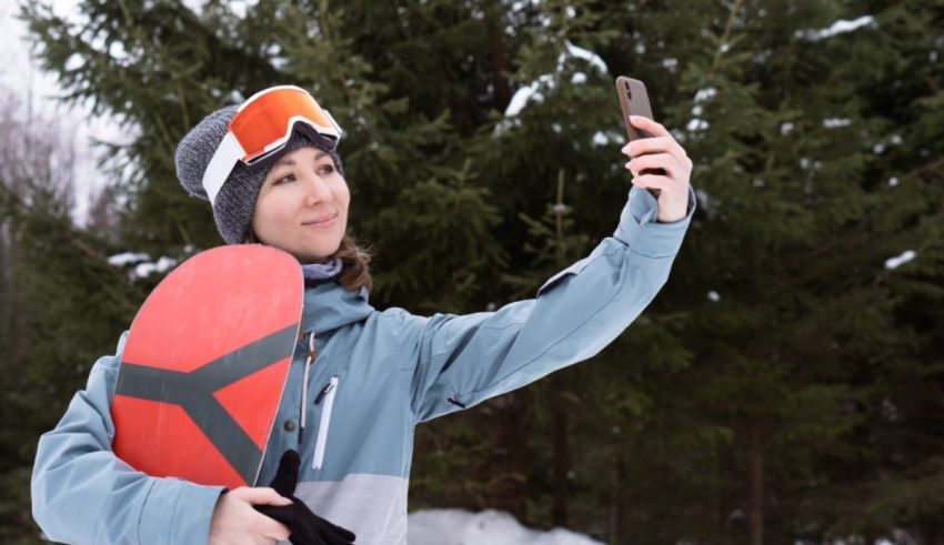 A woman holding a snowboard while taking a selfie.