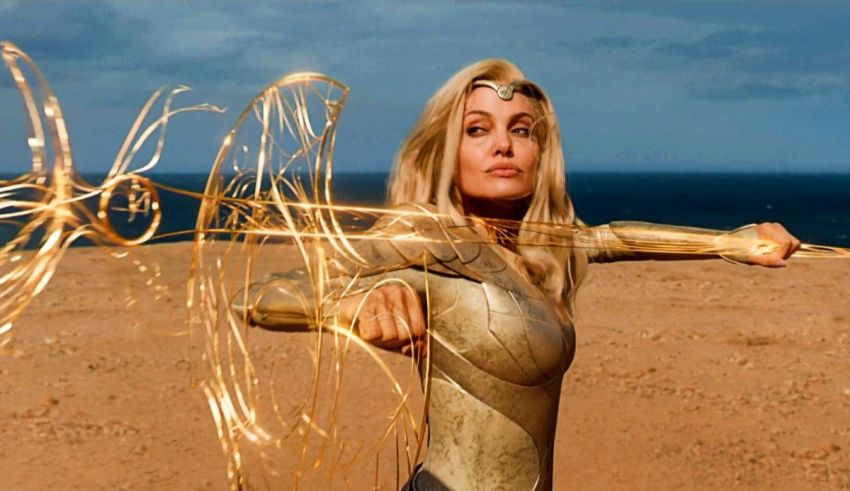 A woman in a gold suit is posing in front of the ocean.