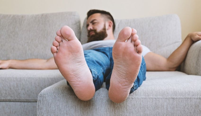 A man's feet resting on a couch.