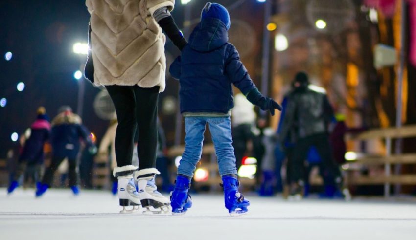 A woman and a child skating on an ice rink at night.