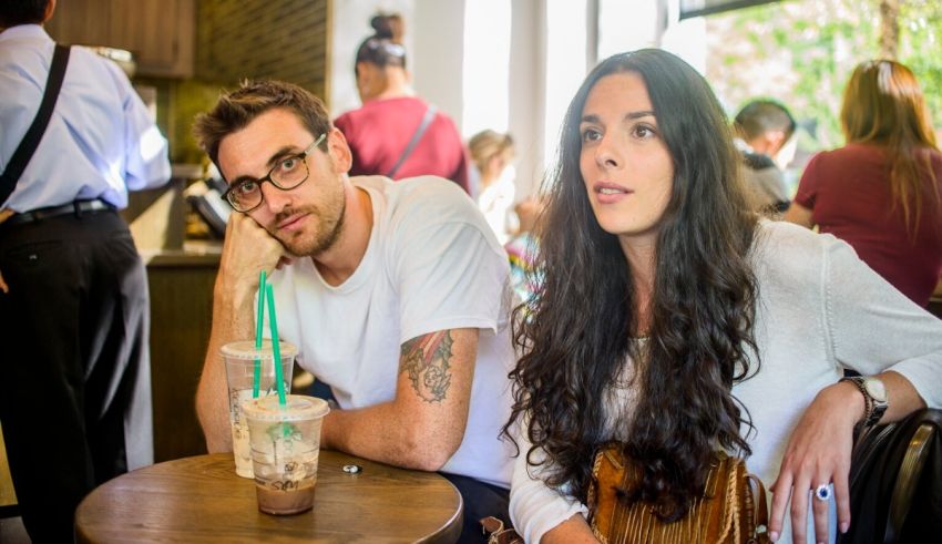 A man and woman sitting at a table with starbucks drinks.