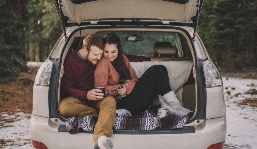 A couple sitting in the trunk of a car.