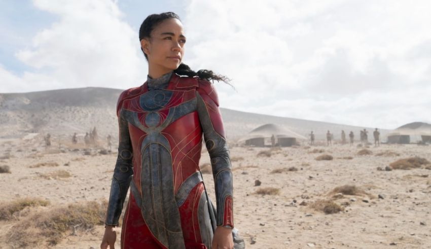 A woman in a red suit standing in a desert.