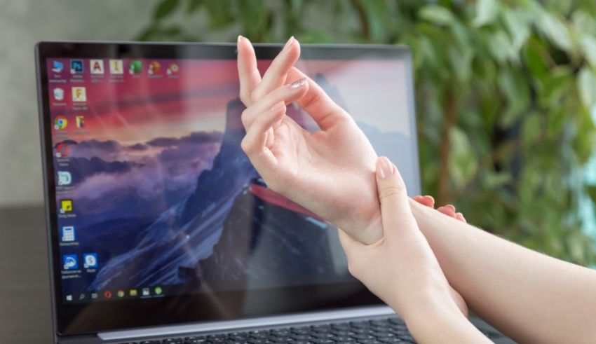 A woman's hand is touching the screen of a laptop.