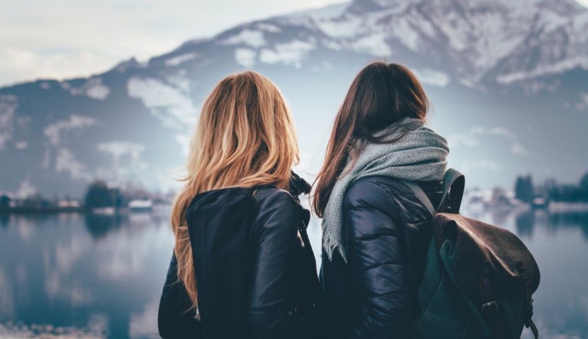 Two women looking at a lake with mountains in the background.