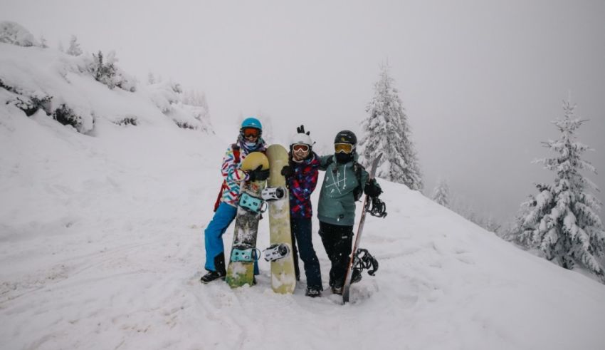 Three people posing with snowboards on a snowy slope.