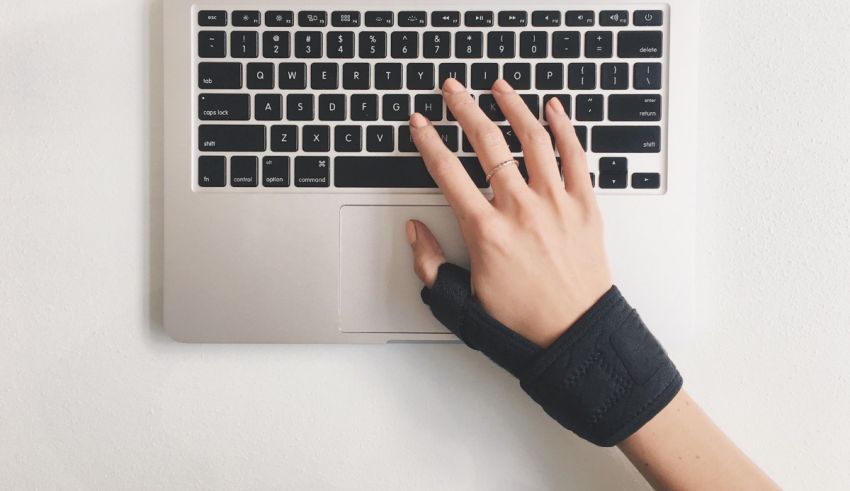 A woman typing on a laptop with a wrist brace.
