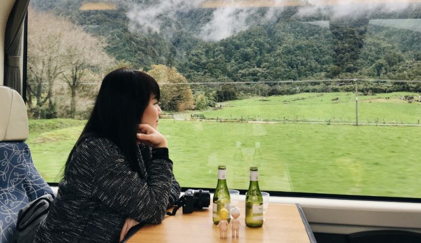 A woman sitting on a train looking out at the countryside.