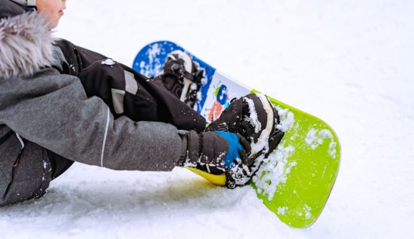 A young boy sitting on a snowboard in the snow.