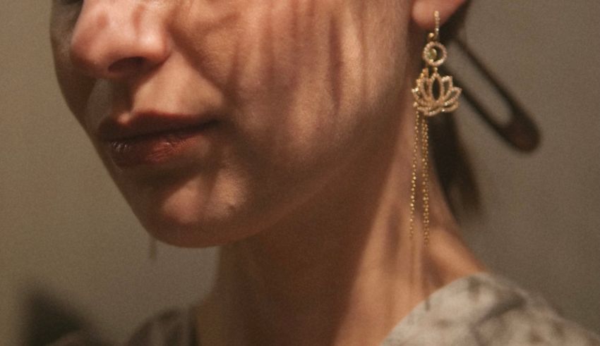 A woman wearing a pair of gold dangling earrings.